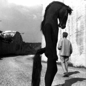 Lucien Clergue photograph: Jean Cocteau walks past the horse-man on the set of Le Testament d'Orphée, 1959